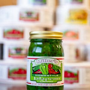 A jar of pickles sitting in front of many other jars.