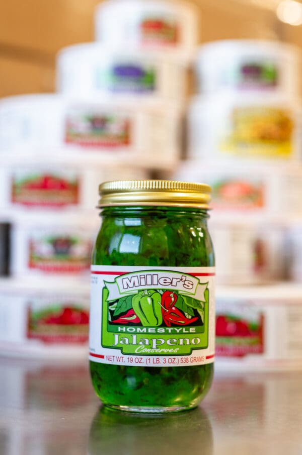 A jar of pickles sitting in front of many other jars.