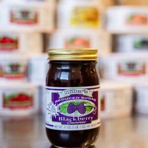 A jar of blackberry jam sitting on top of a table.