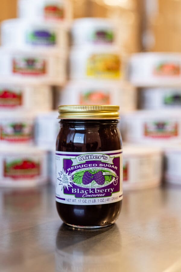 A jar of blackberry jam sitting on top of a table.