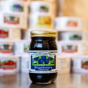 A jar of blueberry jam sitting on top of a table.