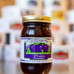 A jar of plum preserves sitting on top of a table.