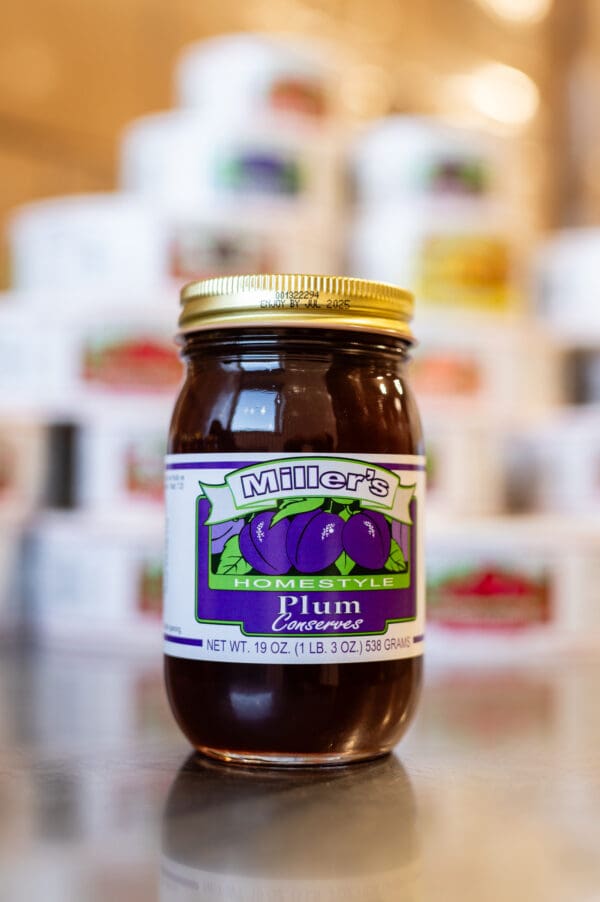 A jar of plum preserves sitting on top of a table.