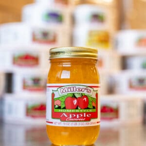 A jar of apple jelly sitting on top of a table.