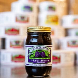 A jar of blackberry jam sitting on top of a table.