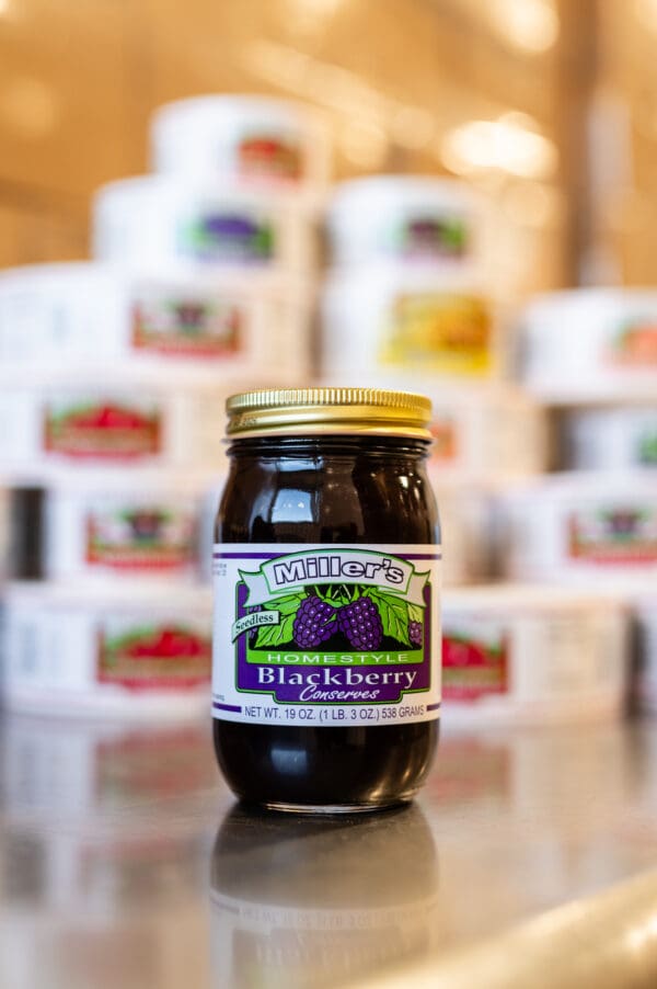 A jar of blackberry jam sitting on top of a table.