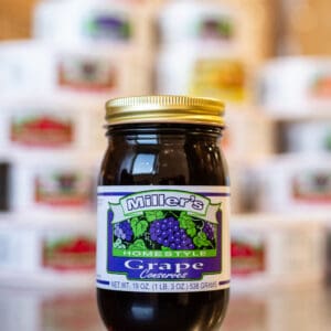 A jar of grape jelly sitting on top of a table.