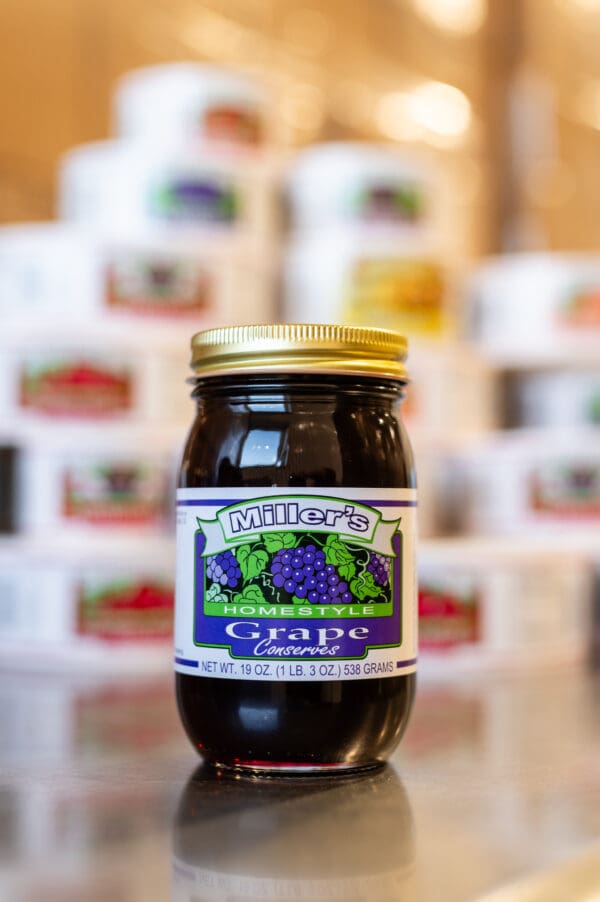 A jar of grape jelly sitting on top of a table.