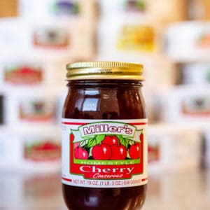 A jar of cherry jelly sitting on top of a table.