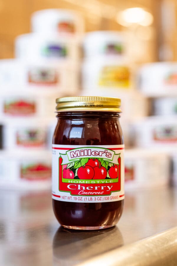 A jar of cherry jelly sitting on top of a table.