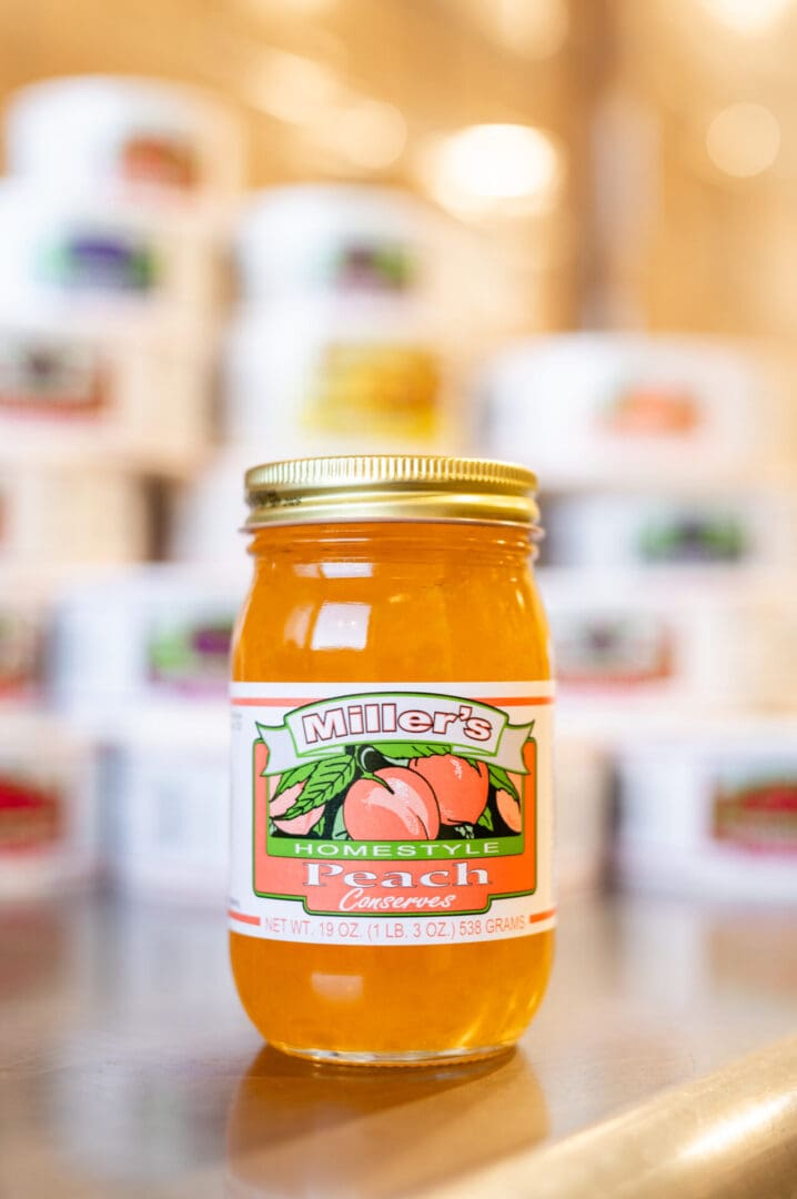 A jar of peach jam sitting on top of a counter.