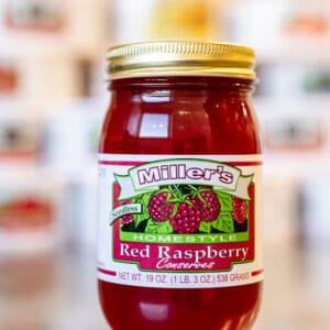 A jar of red raspberry jam on the counter.