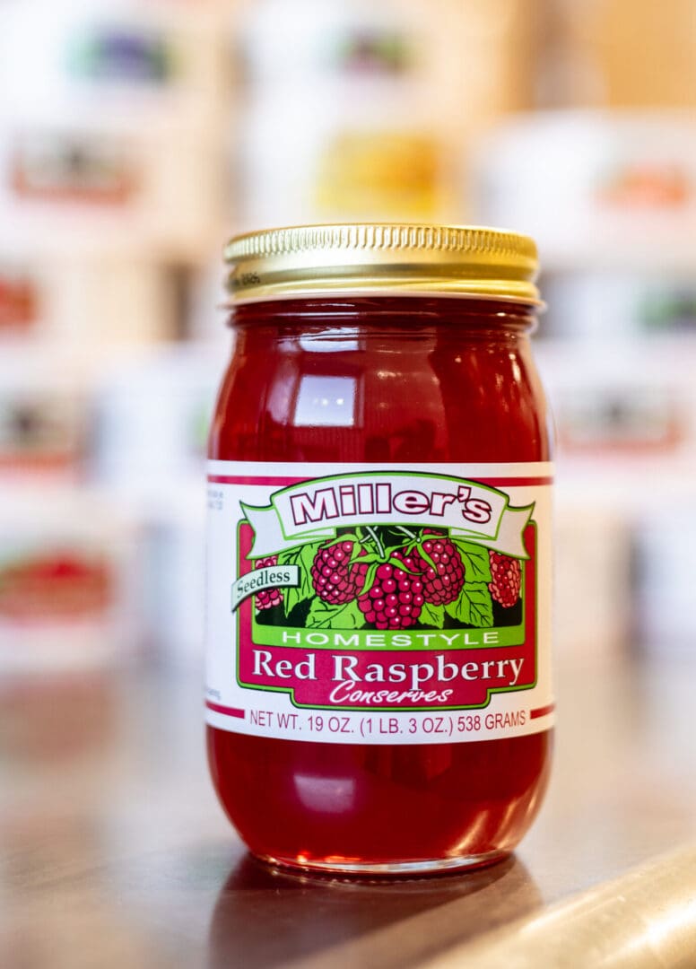 A jar of red raspberry jam on the counter.