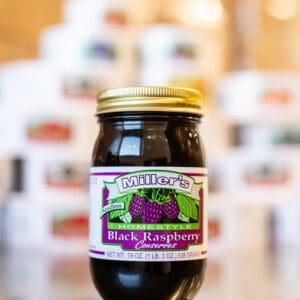 A jar of black raspberry jam sitting on top of a table.