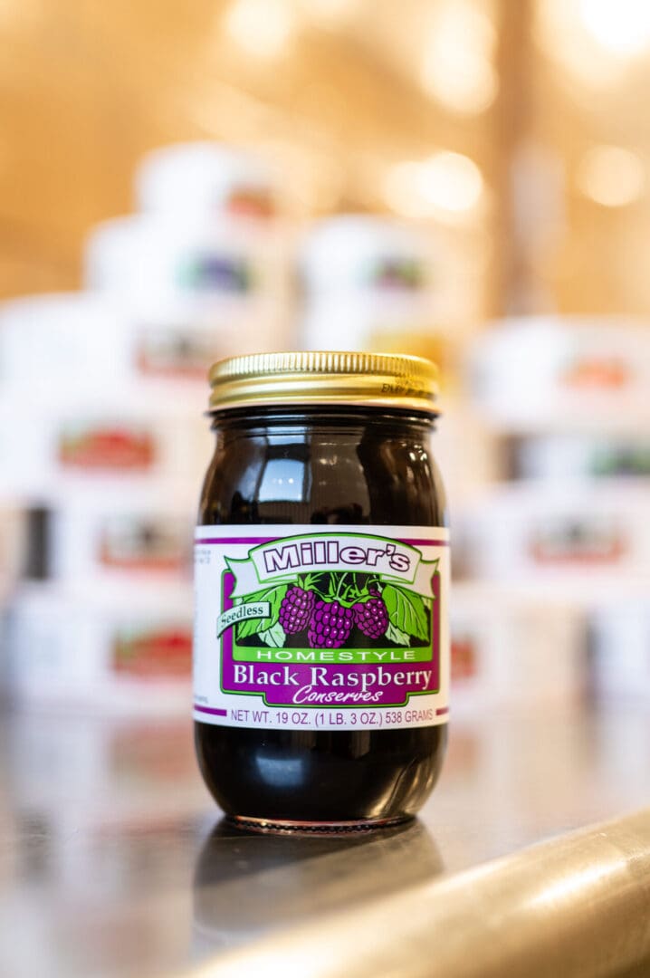 A jar of black raspberry jam sitting on top of a table.