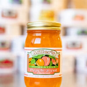 A jar of peach preserves sitting on top of a counter.