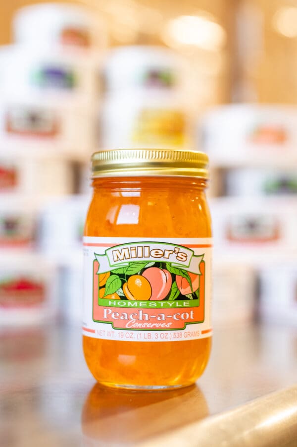 A jar of peach preserves sitting on top of a counter.