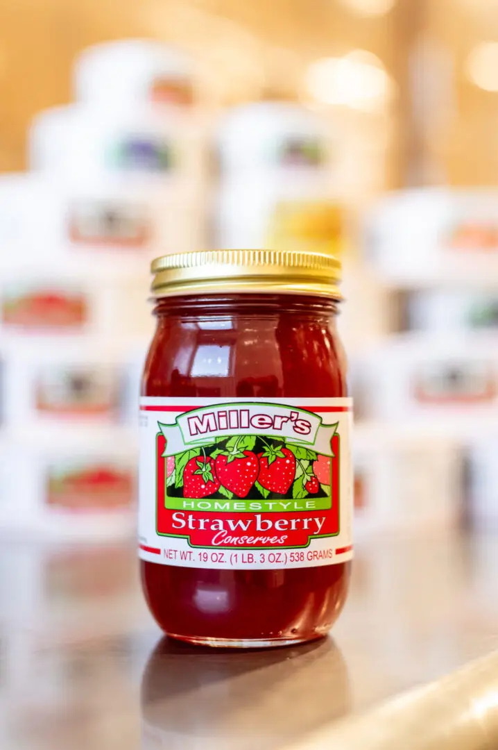 A jar of strawberry preserves on top of a table.