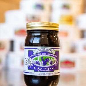 A jar of grape jelly sitting on top of a table.