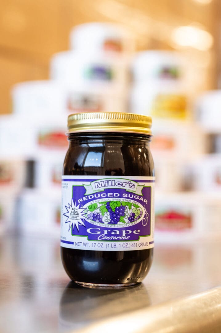 A jar of grape jelly sitting on top of a table.