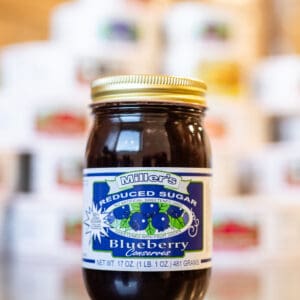A jar of blueberry jam sitting on top of a counter.