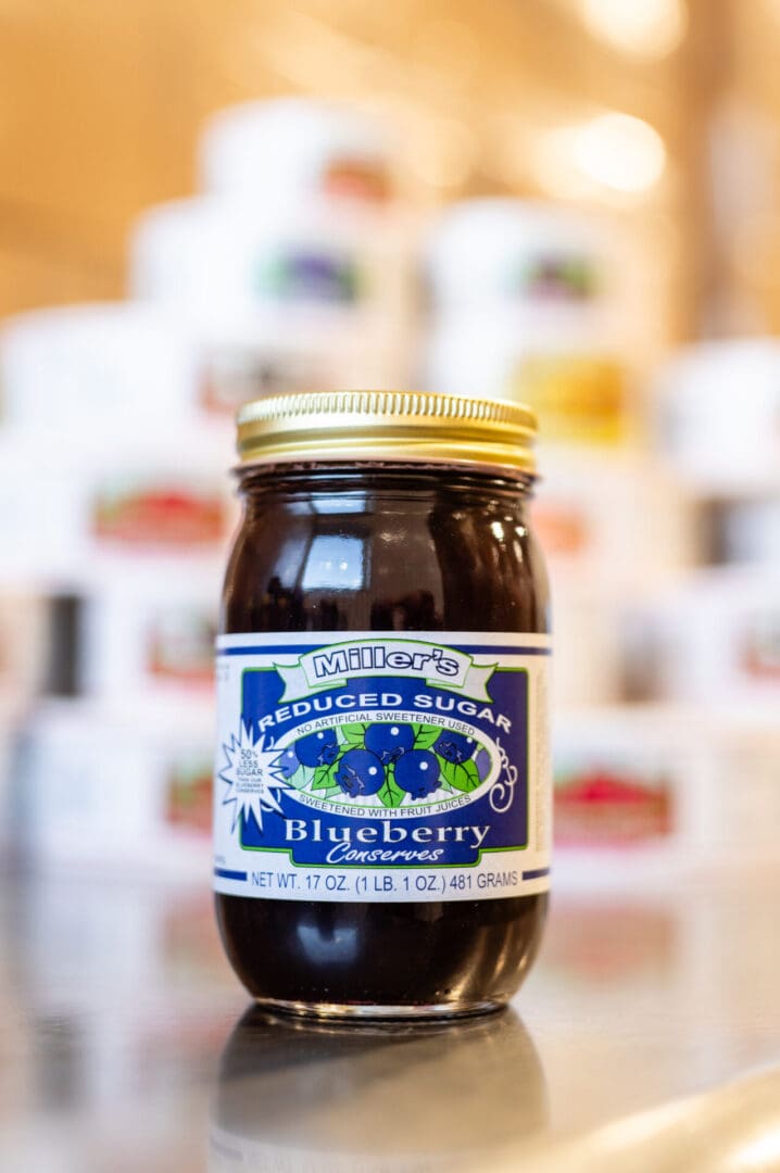 A jar of blueberry jam sitting on top of a counter.