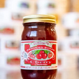 A jar of cherry jam sitting on top of a table.