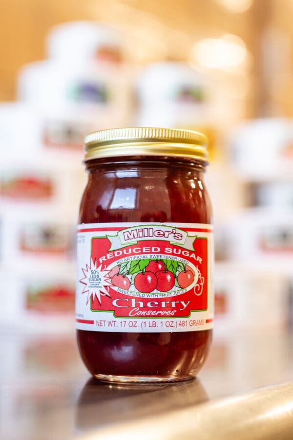 A jar of cherry jam sitting on top of a table.