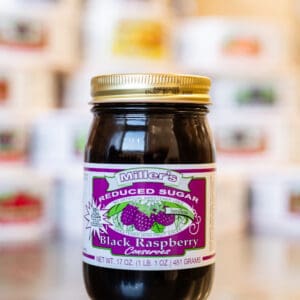 A jar of black raspberry jam on top of a table.