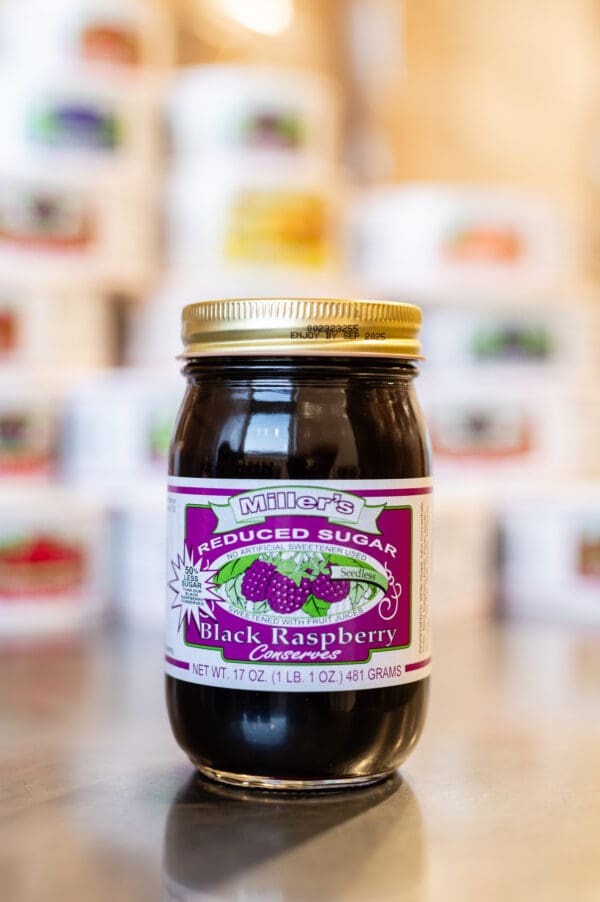 A jar of black raspberry jam on top of a table.