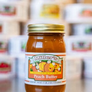 A jar of peach butter sitting on top of a counter.