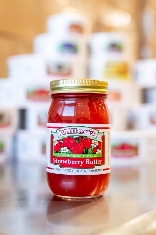 A jar of strawberry butter sitting on top of a table.