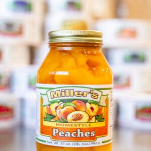 A jar of peaches is sitting on the counter.