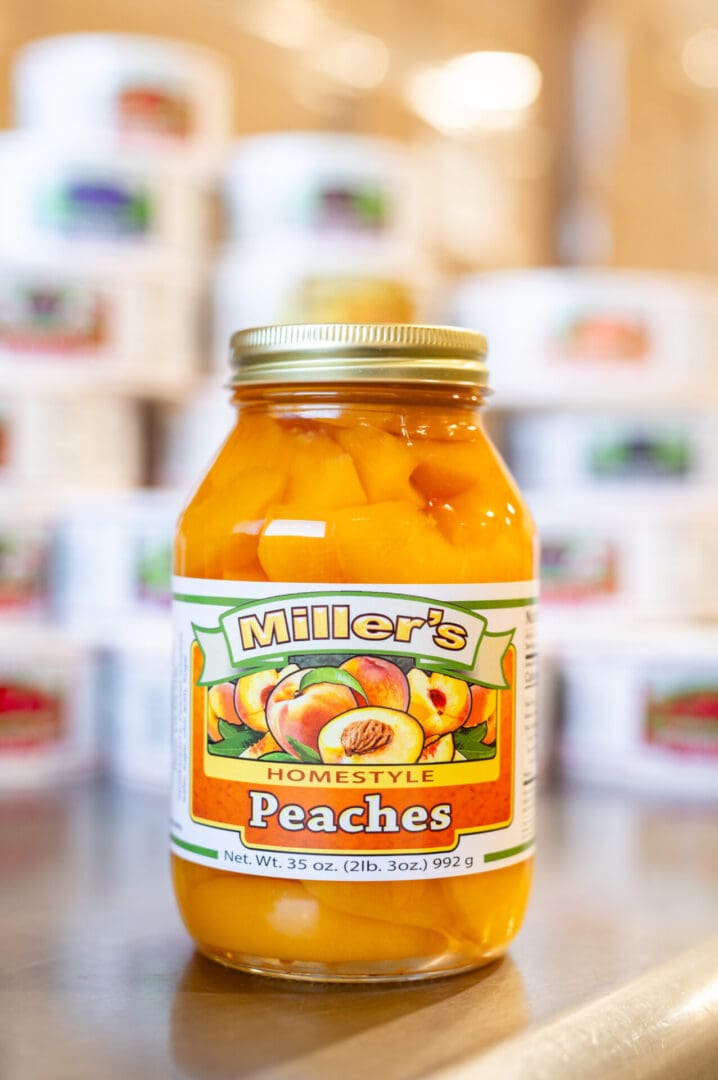 A jar of peaches is sitting on the counter.