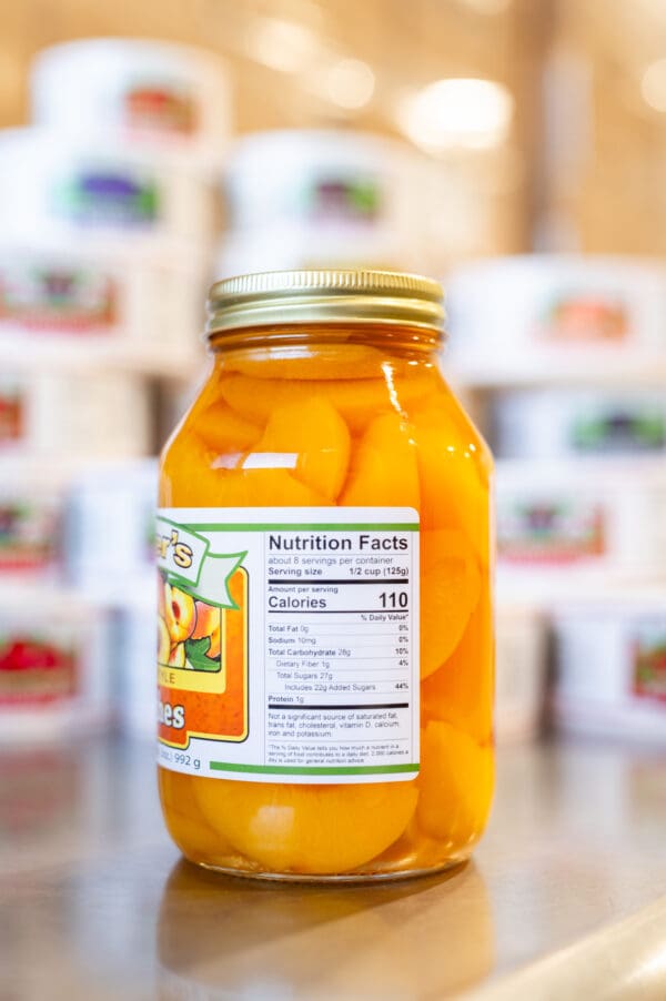 A jar of canned peaches sitting on top of a counter.