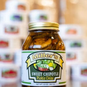 A jar of pickles sitting in front of many other jars.