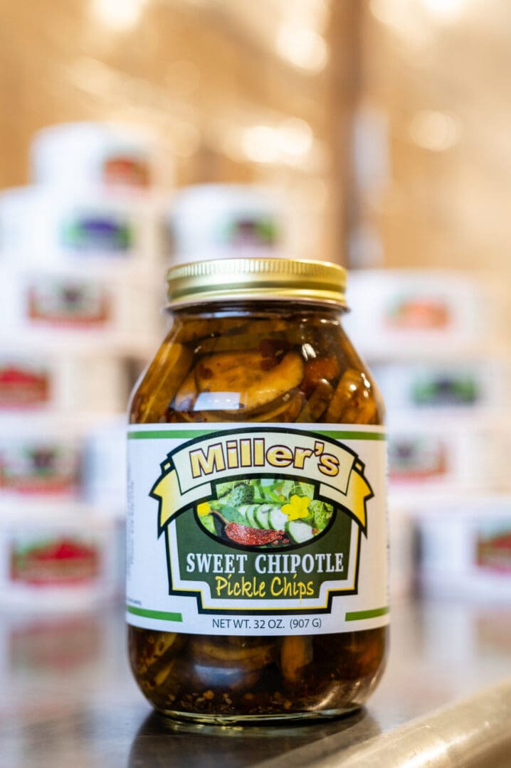 A jar of pickles sitting in front of many other jars.