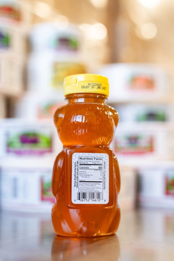 A bottle of honey is sitting in front of other boxes.